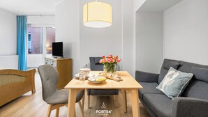 A modern living room with a wooden dining table, grey sofa, and a hanging lamp. - "Ferienwohnung Krebs" in the heart of Büsum with balcony and close to the beach (Büsum)