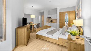 A modern hotel room with a wooden bed, a desk, a TV, and a kitchenette. - "Ferienwohnung Krebs" in the heart of Büsum with balcony and close to the beach (Büsum)