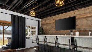 Eine moderne Küche mit Bar, Holzbalkendecke und einem großen Fenster mit Vorhängen.