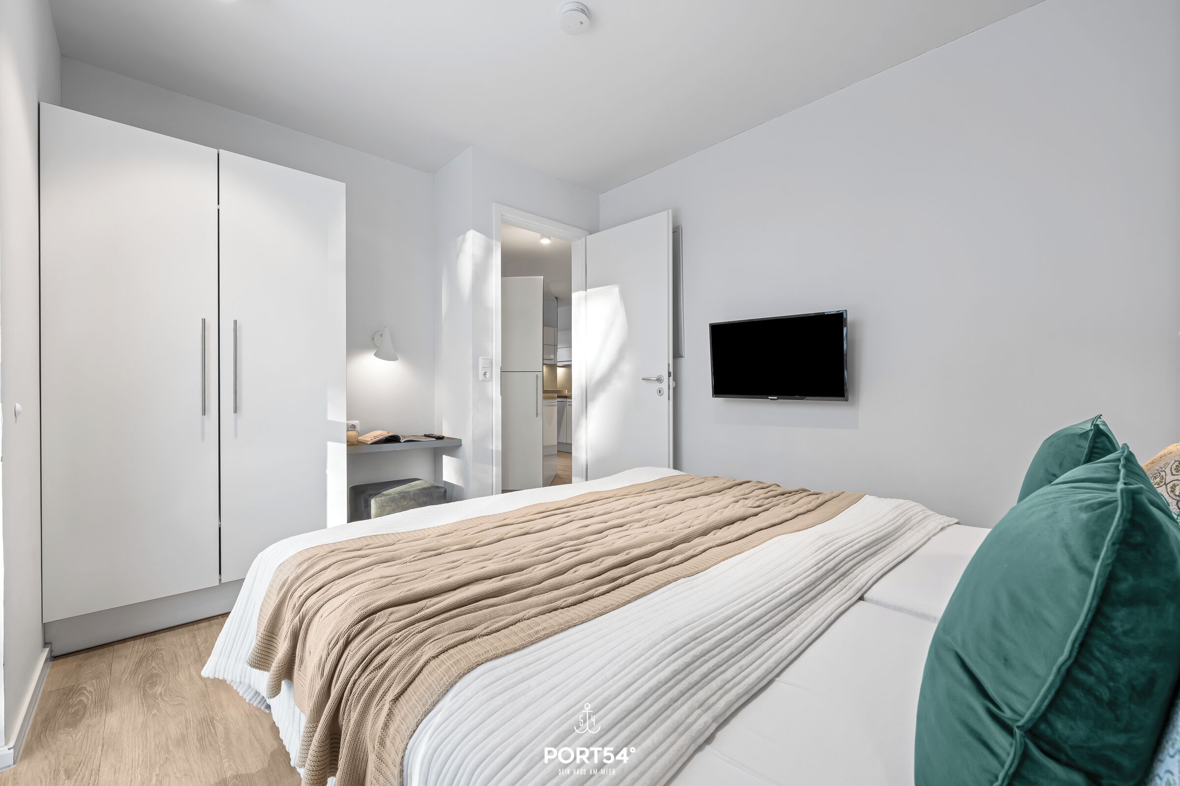 Un dormitorio moderno con una cama, un televisor y un armario.