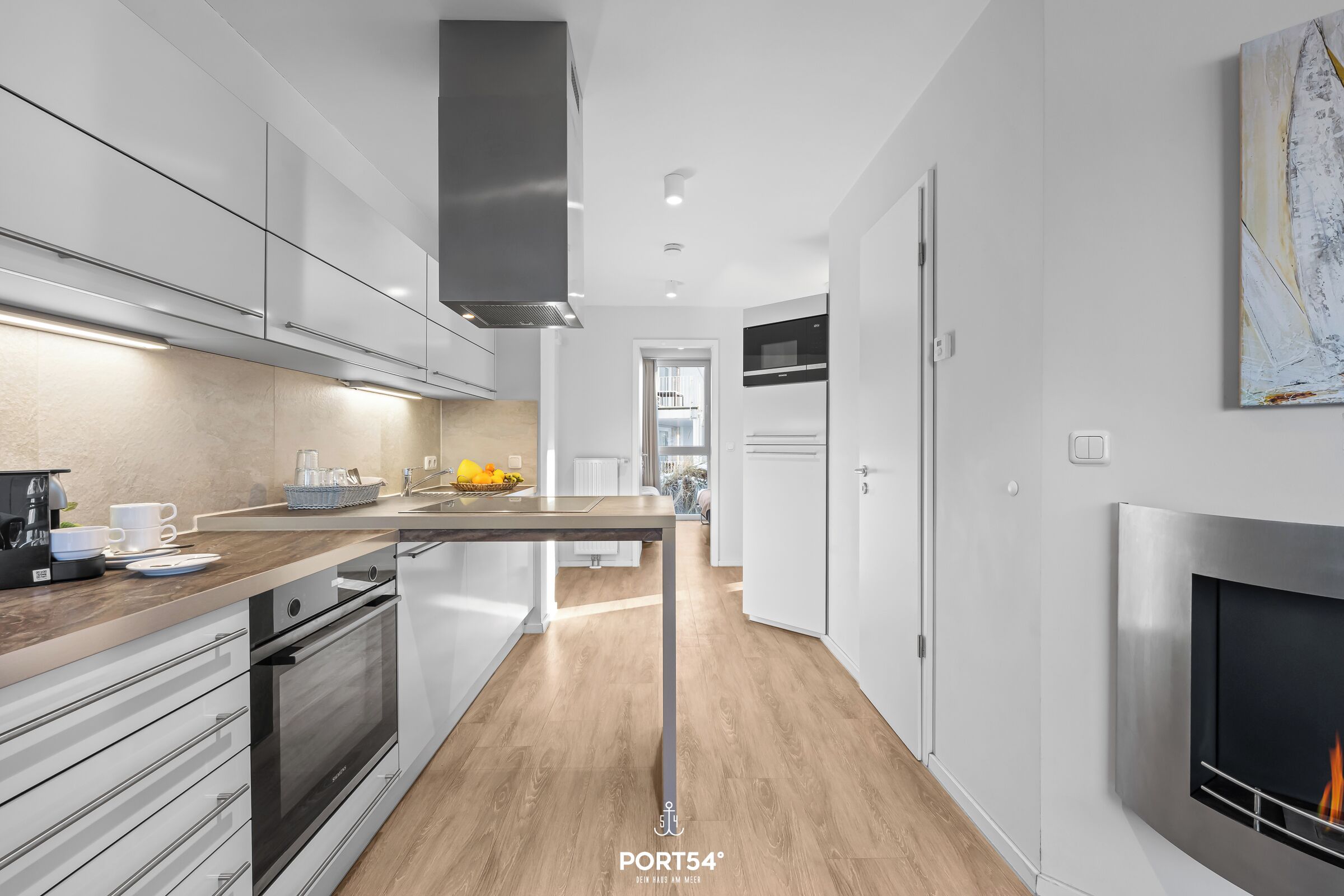 A modern kitchen with stainless steel appliances, a central island, and a fireplace.