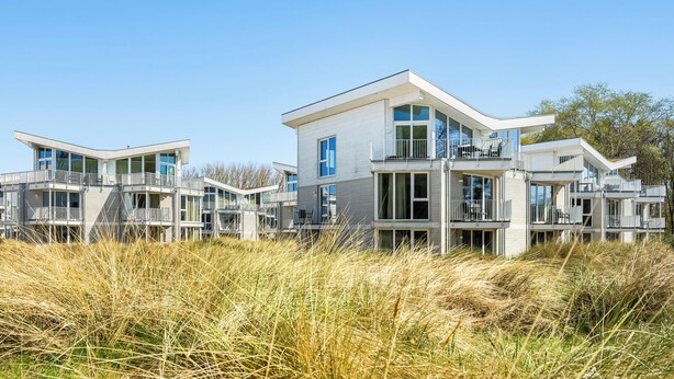 A modern multi-story residential building with balconies and large windows. - Bright Family Apartment with Covered Balcony and Wellness near Priwall Beach (Lübeck)