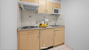 Una cocina con armarios de madera, un microondas, una cafetera y un bol de frutas sobre la encimera.