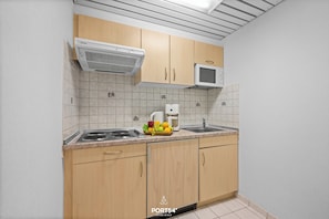 Eine Küche mit Holzausstattung, einer Mikrowelle, einer Kaffeemaschine und einer Obstschale auf der Arbeitsfläche.