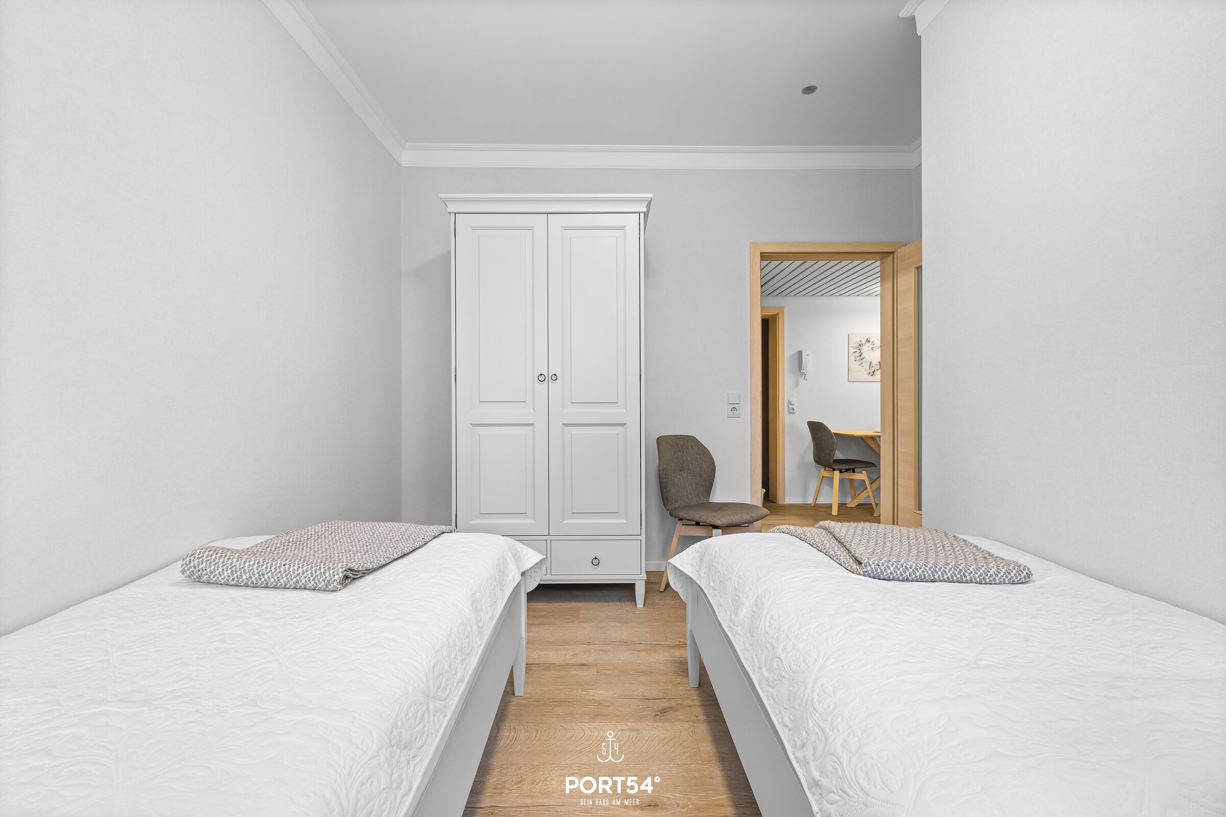 Una camera da letto con due letti, un armadio e una scrivania con una sedia.