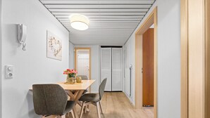 Un comedor moderno con una mesa y sillas de madera, una lámpara en el techo y un teléfono en la pared.