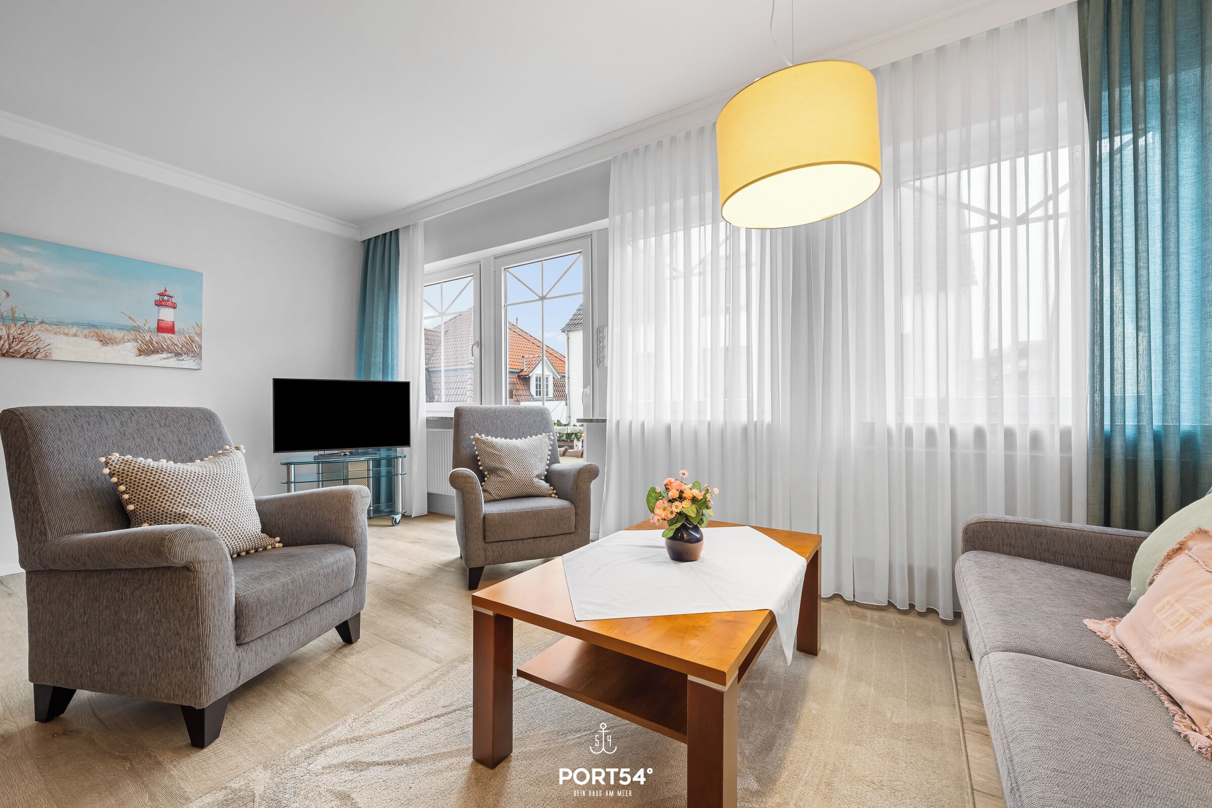 A modern living room with a grey sofa, armchairs, a wooden coffee table, and a TV.
