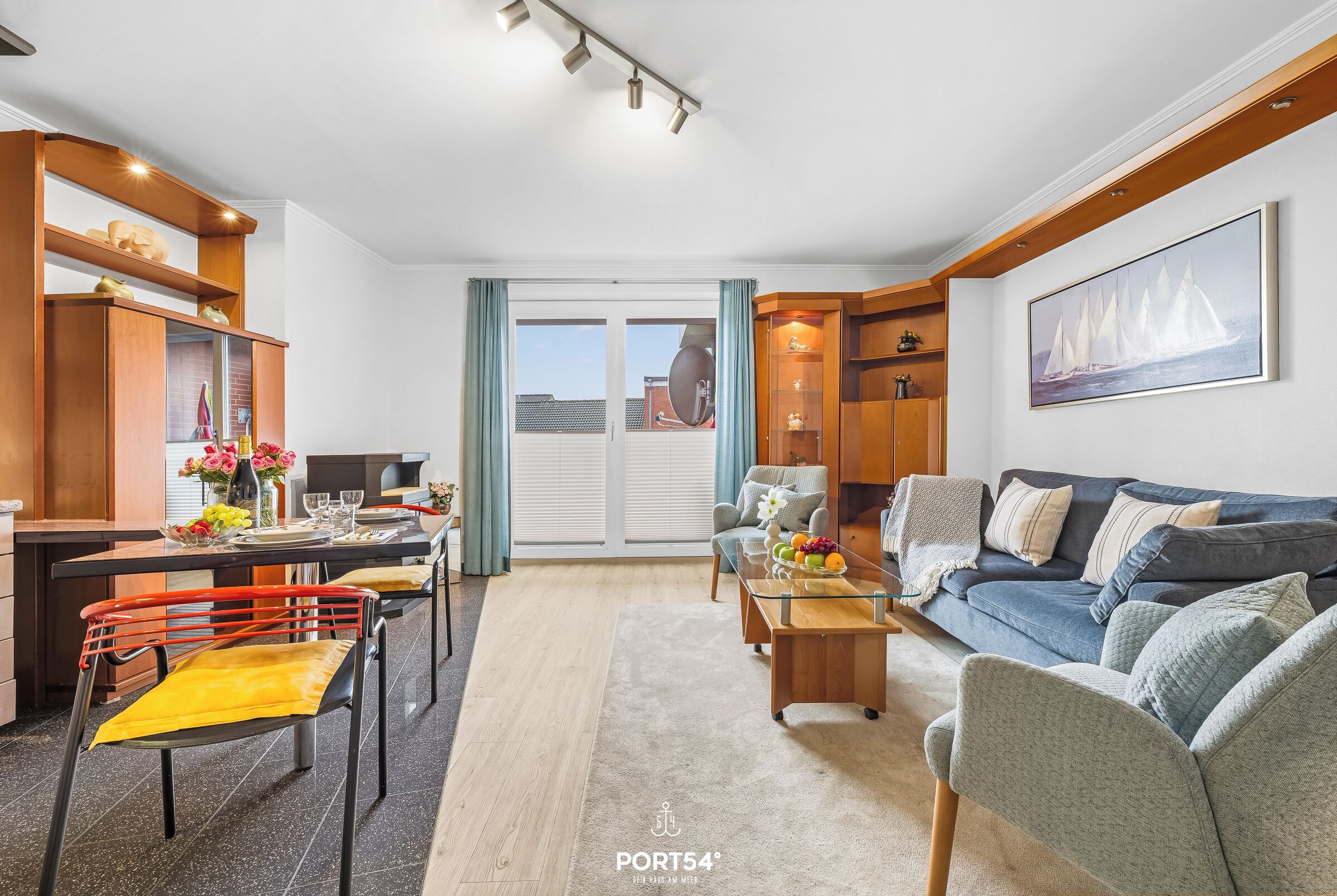 A modern living room with a dining area, a sofa, a coffee table, and a kitchen area with a dining table and chairs. - "Ferienwohnung Muschel" in the heart of Büsum with balcony, center and close to the beach (Büsum)
