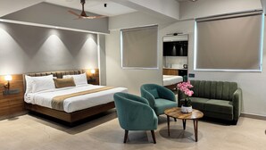 A modern hotel room with a large bed, two armchairs, a small round table, and a sofa. - MALPE RIVIERA (Udupi)