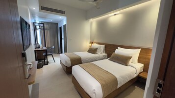 Habitación de hotel con dos camas, un escritorio y una silla.
