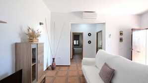 Ein modernes Wohnzimmer mit einer Couch, einem Fernseher, einem Holzschrank und einem Gang zu einem weiteren Raum.