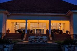 A house with a front porch, a stone bench, and a staircase leading to the entrance. - Martha's Farm House (Mukono)