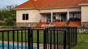 Uma casa com piscina, varanda coberta e muro de pedra.