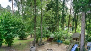 Ein Spielplatz mit Rutsche, Schaukeln und einem Picknicktisch inmitten eines bewaldeten Bereichs.