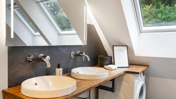 A modern bathroom with skylights, a double sink, and a framed picture on the wall.