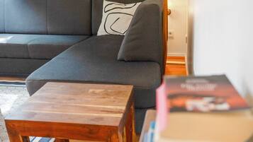 A sectional sofa with a pillow, a wooden coffee table, and a magazine on a table.