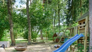 Ein Spielplatz mit Rutsche, Schaukeln und einer kleinen Holzkonstruktion.