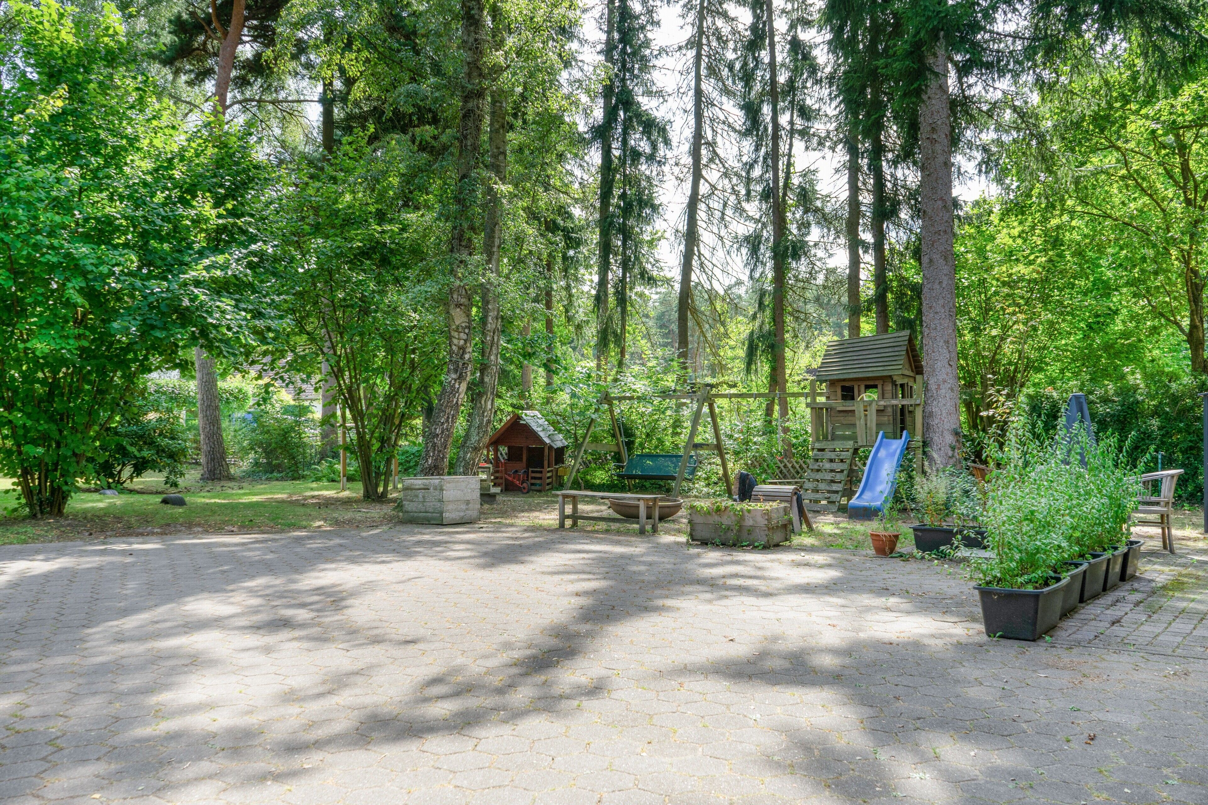En campingplats med picknickbord, en lekplats och en liten stuga.