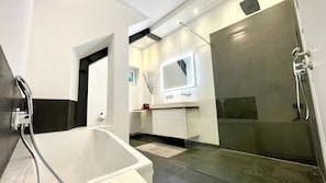 A modern bathroom with a bathtub, a shower, and a vanity with a mirror.