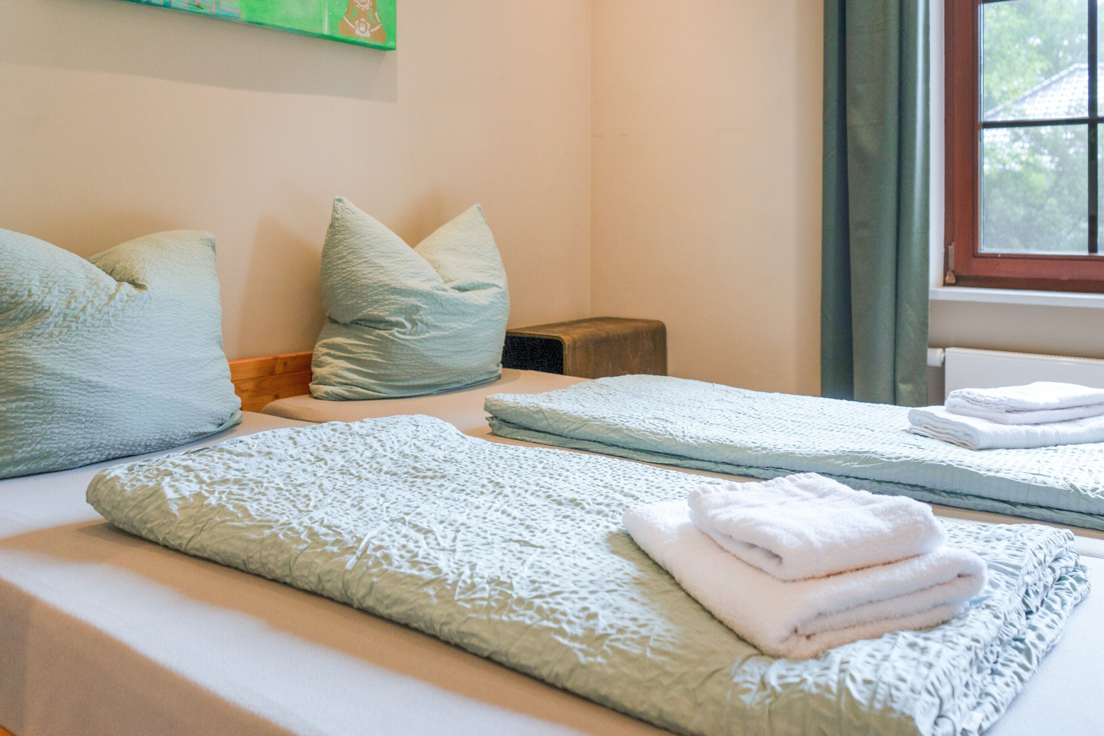 Hotellihuone, jossa on kaksi sänkyä, ja kummassakin on siististi taitettu valkoinen pyyhe.