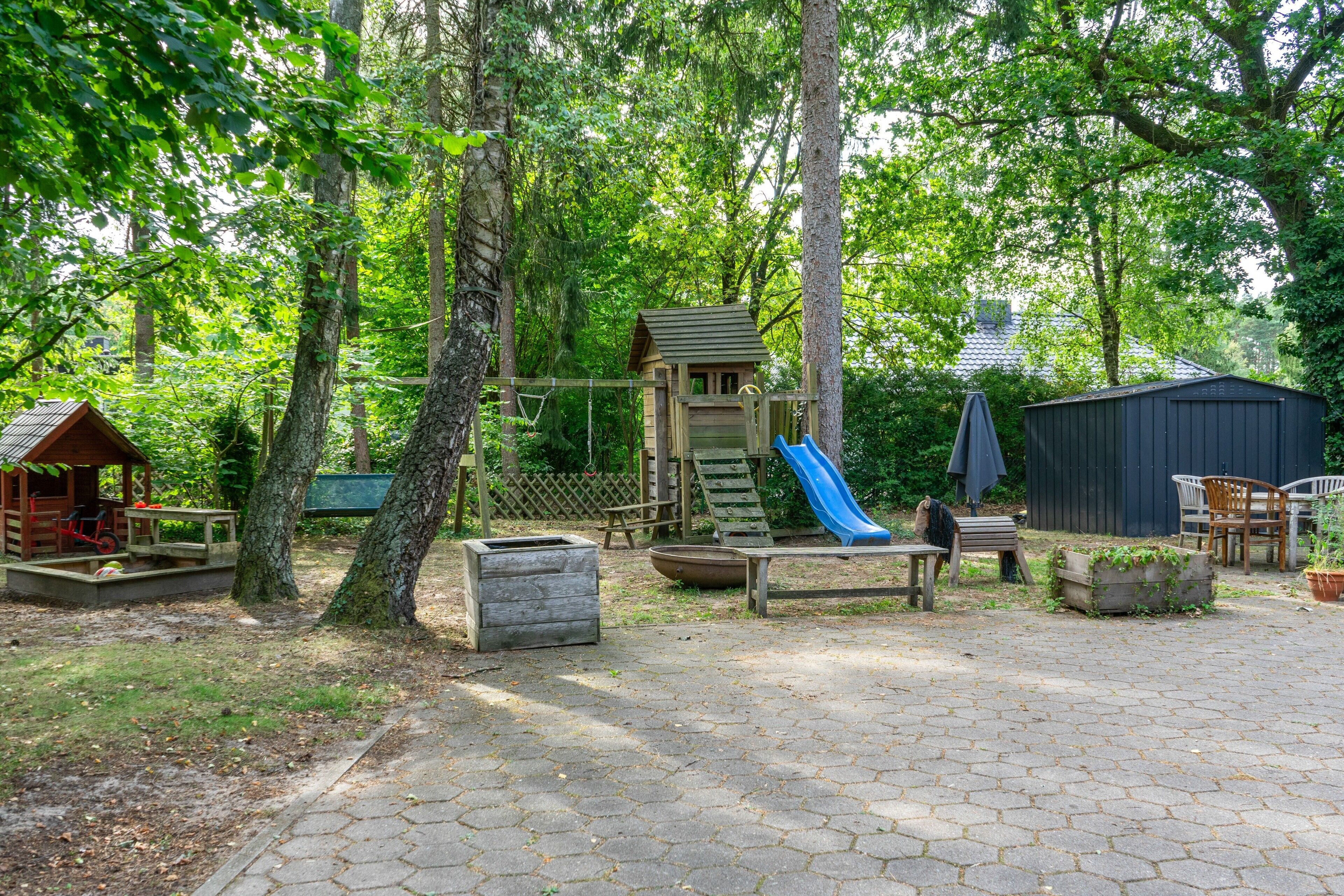 A playground with a slide, swings, and a small wooden structure.
