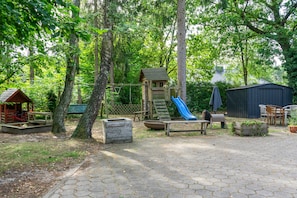 A playground with a slide, swings, and a small wooden structure. - Stayplace Nr. 2: Geräumige moderne Design-Wohnung (Garstedt)
