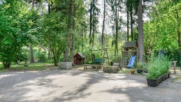 Een camping met picknicktafels, een speelruimte en een klein huisje.