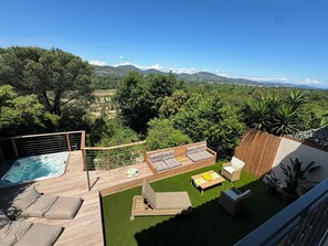 Terrassa a la teulada amb banyera d'hidromassatge, mobiliari exterior i vista a un paisatge muntanyós.