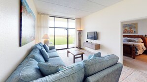 Un salon avec un canapé, un téléviseur et une chambre à coucher dans la pièce adjacente.