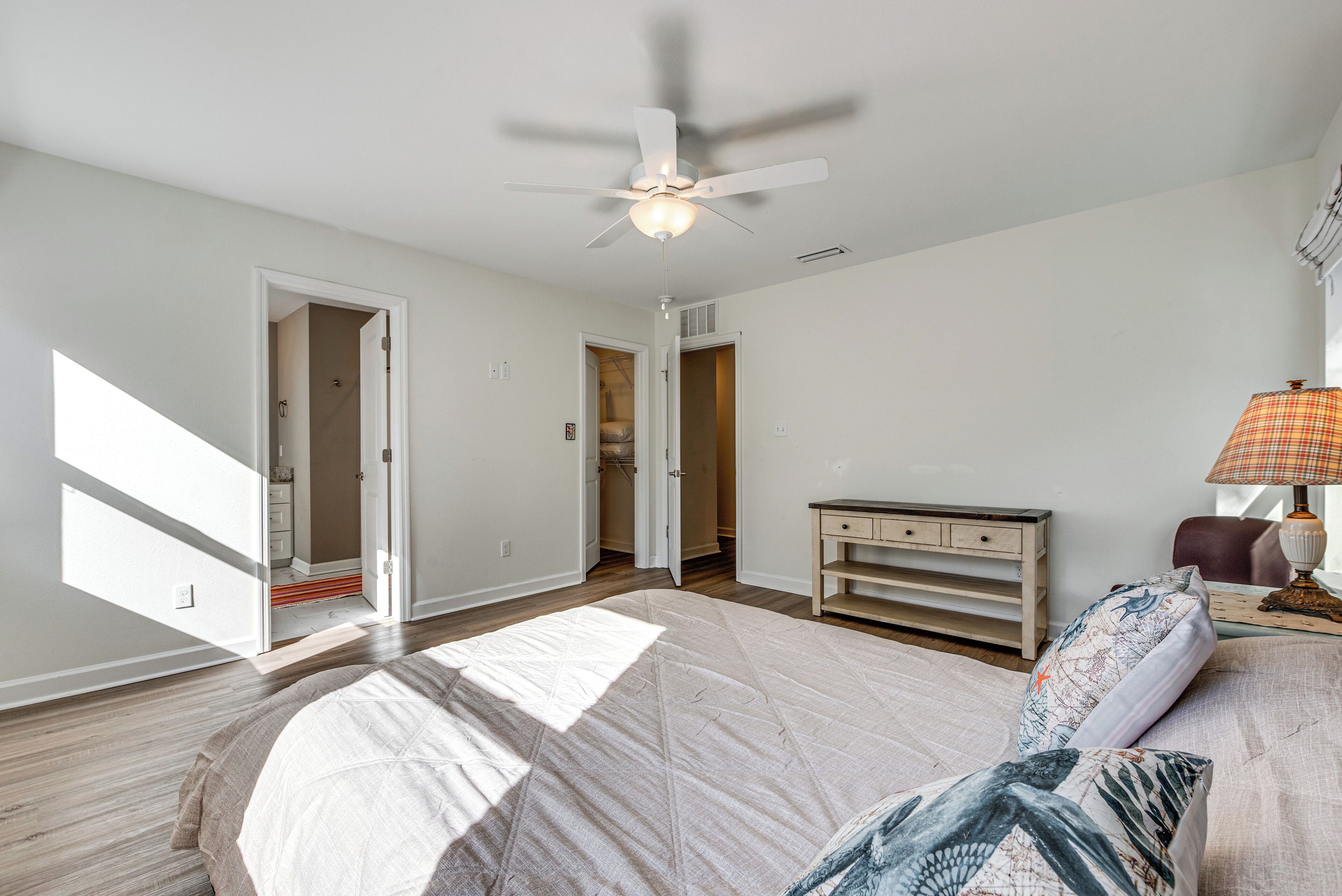 Un dormitorio con cama, ventilador de techo, mesita de noche y lámpara.