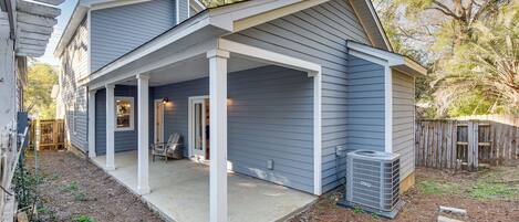 A two-story house with a covered porch and a small backyard.