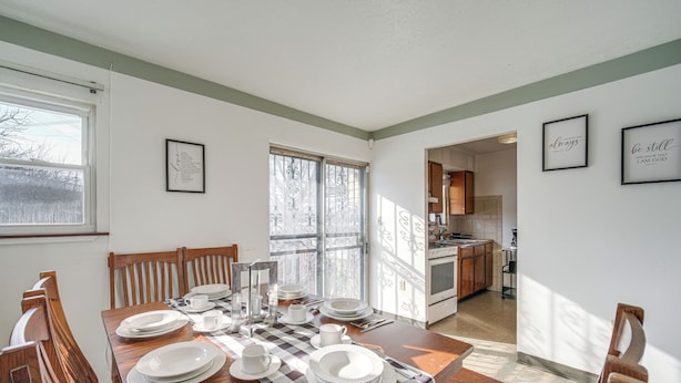 A dining area with a wooden table set for four, chairs, and a kitchen in the background. - Red Line to Airport! Inviting Home in Cleveland (East Cleveland)