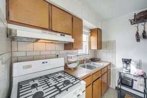 A kitchen with wooden cabinets, a white stove, a sink, and a coffee maker. - Red Line to Airport! Inviting Home in Cleveland (East Cleveland)