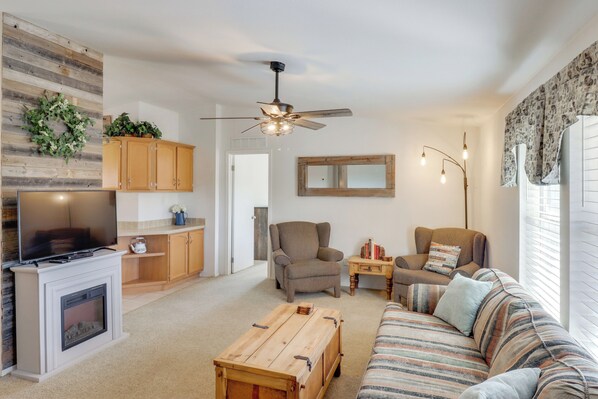 Ein Wohnzimmer mit Kamin, Fernseher, Sofa und Deckenventilator.