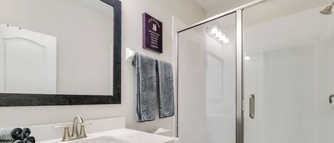 A bathroom with a white sink, dark wood vanity, a glass shower enclosure, and a toilet.