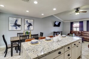 A modern kitchen with a granite island, dining area with chairs, a television, and a leather couch. - Private Pool, Patio! Modern North Las Vegas Escape (Las Vegas)