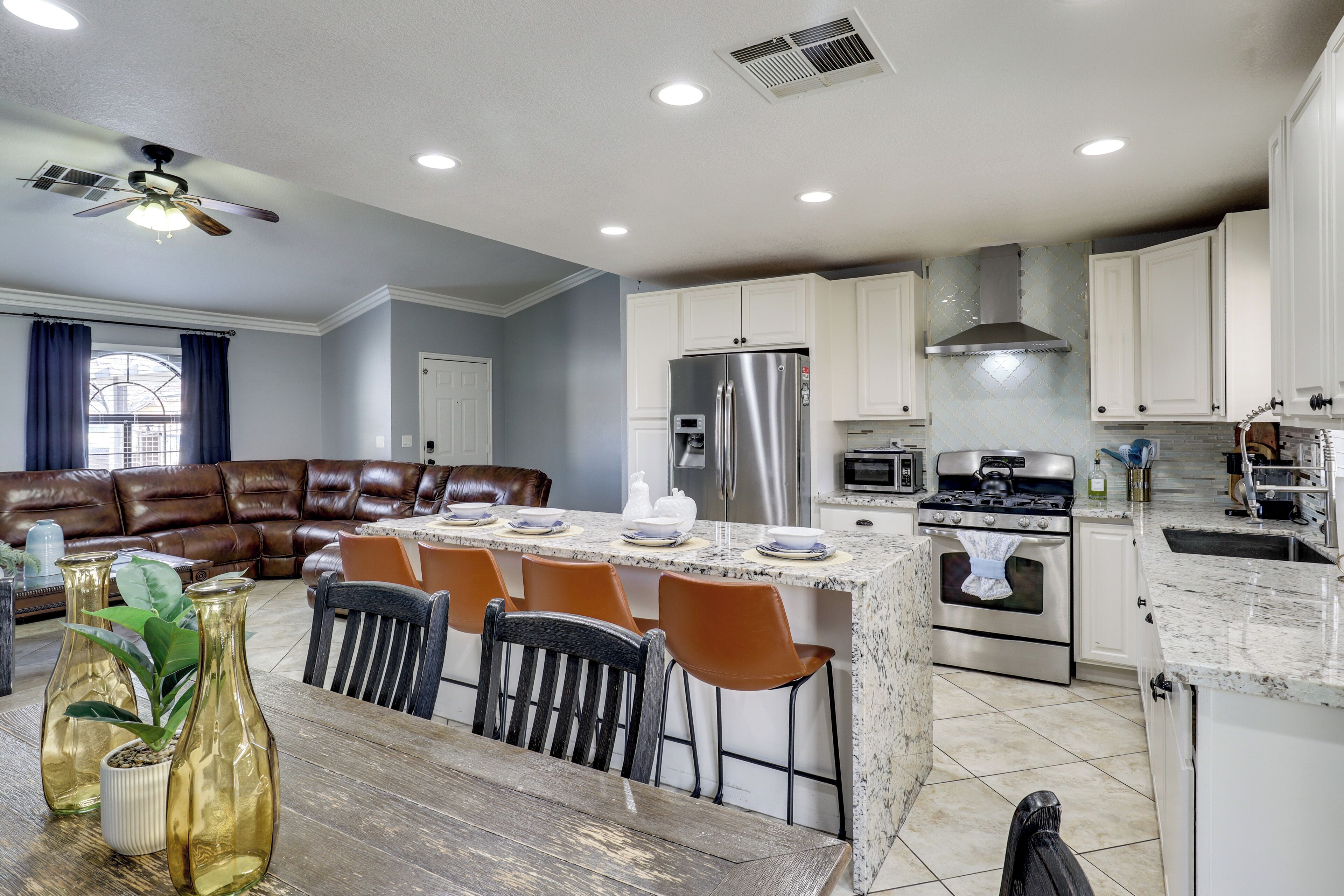 A modern kitchen with white cabinets, a stainless steel refrigerator, and a granite countertop.