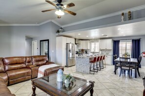 A spacious living room with a brown leather sofa, a glass coffee table, and a ceiling fan. - Private Pool, Patio! Modern North Las Vegas Escape (Las Vegas)
