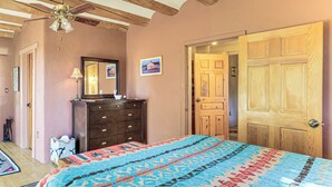 Un dormitorio con cama, cómoda y puerta que da a otra habitación.