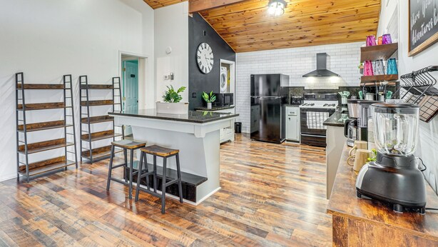 A modern kitchen with a wooden ceiling, white walls, and a black clock. - Mtn & Lake Norris Views: Family Home w/ Game Room! (La Follette)