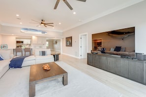 A modern living room with a sofa, coffee table, and a kitchen area with a dining table. - Walkable Waterfront Paradise: Home in Clearwater! (Clearwater Beach)