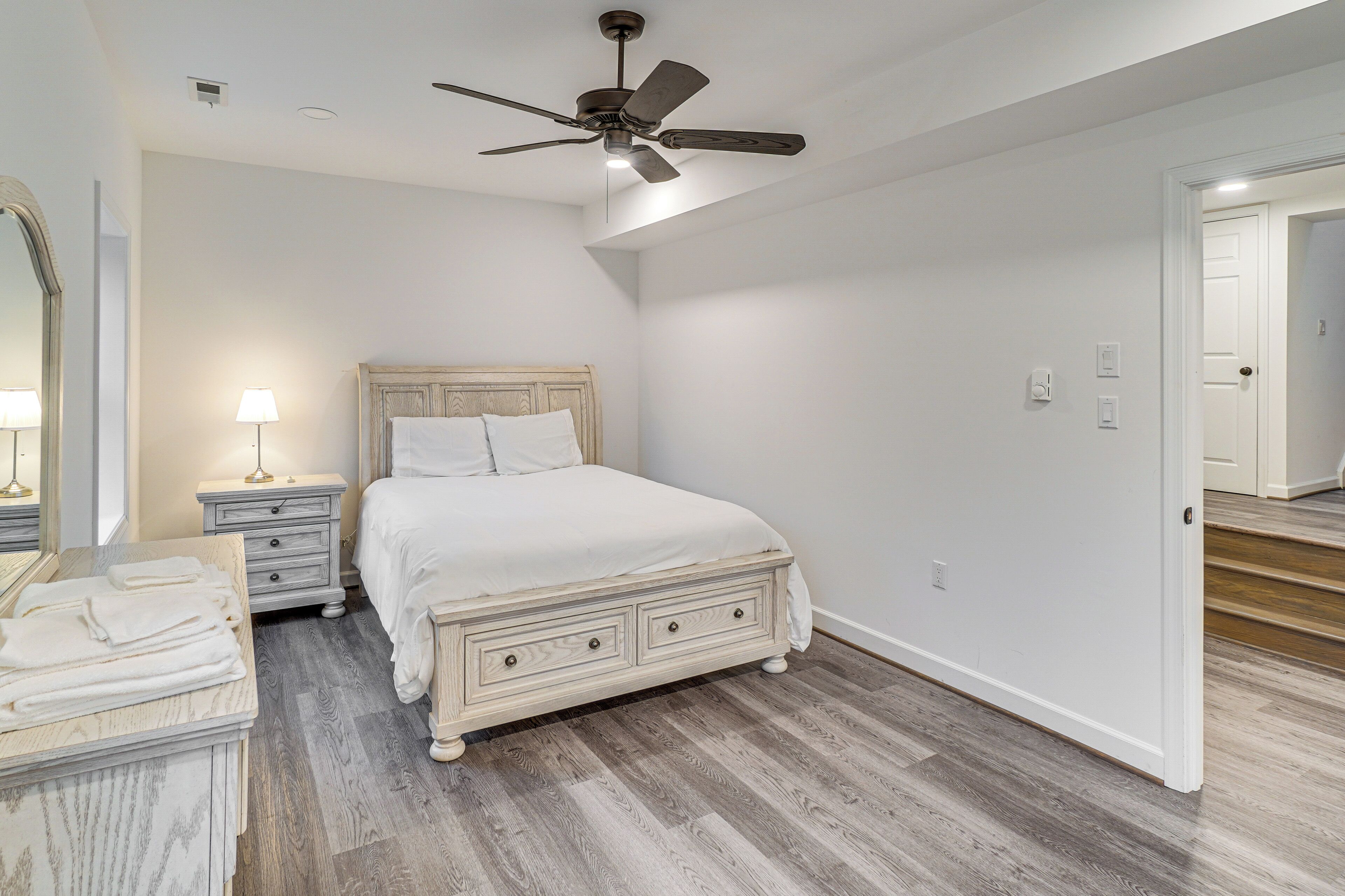 A bedroom with a bed, nightstands, a dresser, and a ceiling fan.