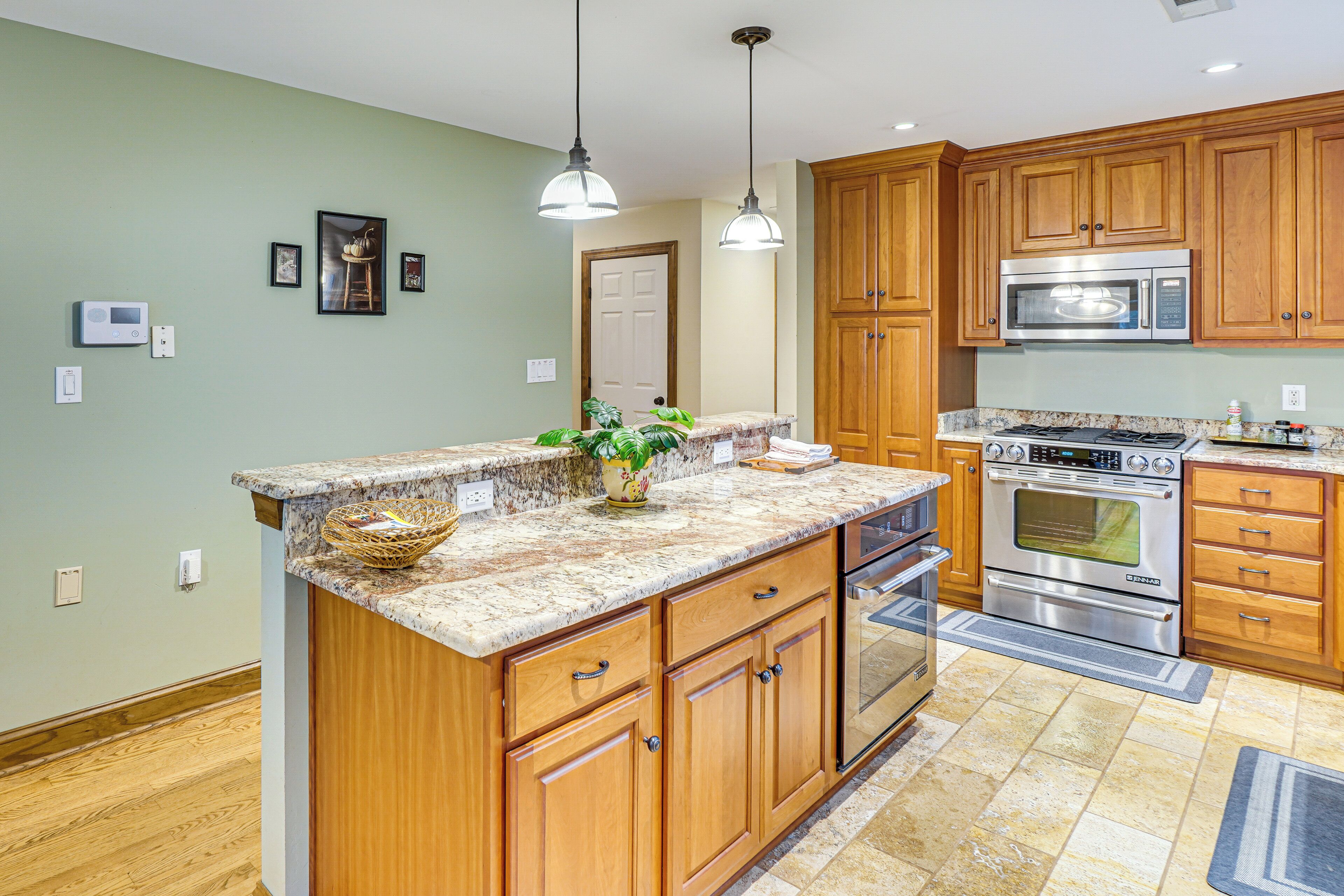 A kitchen with wooden cabinets, granite countertops, stainless steel appliances, and pendant lighting.