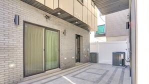 A modern building with a brick facade, large sliding glass doors, and a tiled patio area. - Spacious & Upscale Family Retreat: 5 Mi to NYC (Jersey City)