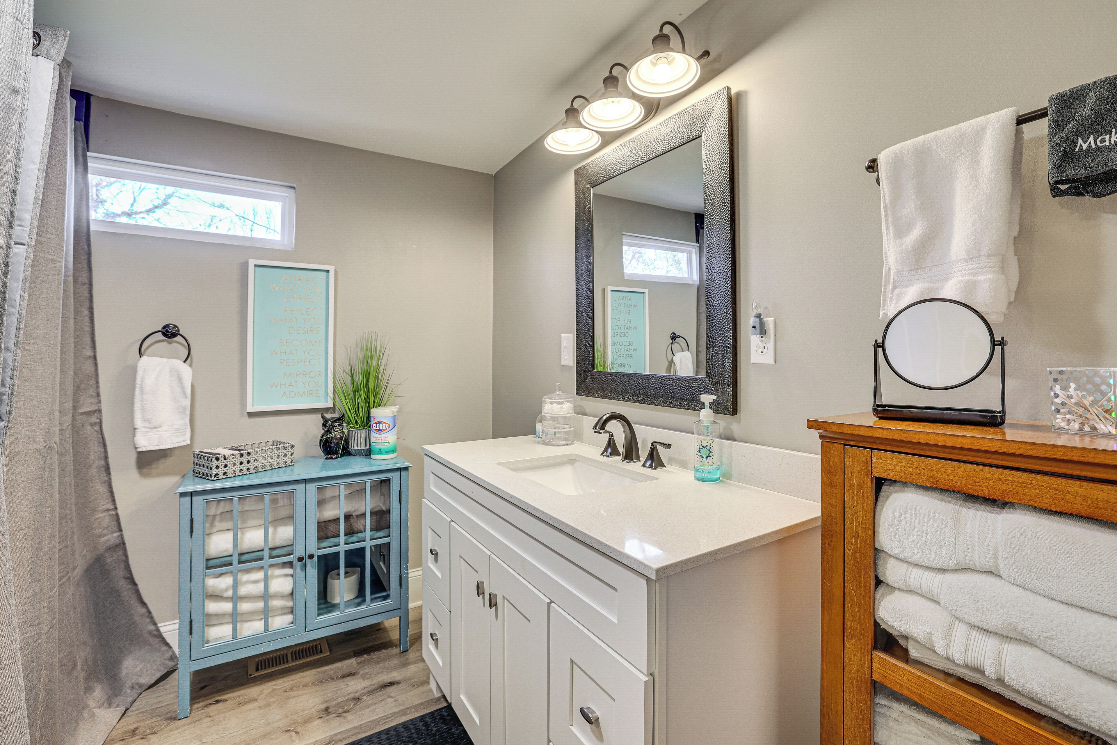 A bathroom with a white sink, a large mirror, and a vanity with a wooden sideboard.