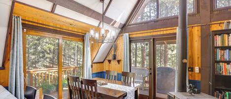 Un intérieur en bois comprenant une table à manger, des chaises, une cheminée et de grandes fenêtres.