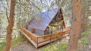 Eine Hütte mit einer Terrasse, umgeben von Bäumen.