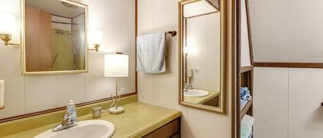 Une salle de bain équipée d’un lavabo, d’un miroir, d’un porte-serviettes et d’un espace douche.