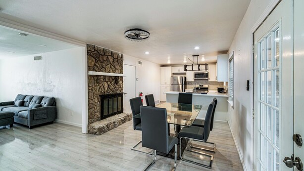 A modern living room with a fireplace, a dining area with a glass table, and a kitchen with stainless steel appliances. - Family + Pet Friendly! Garland Home w/ Fenced Yard (Garland)