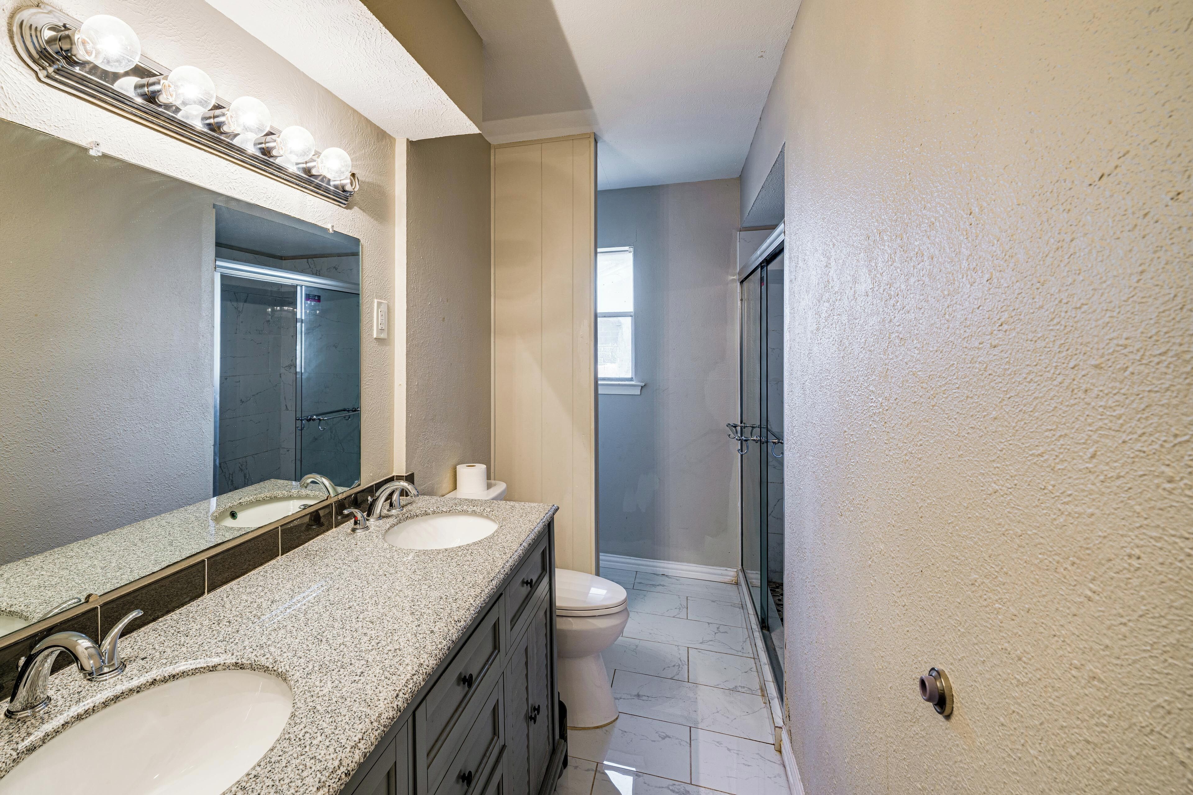 A bathroom with two sinks, a mirror, and a shower.